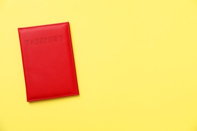 Photo of Passport in bright cover on yellow background, top view. Space for text