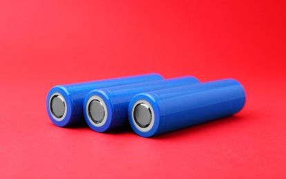 Photo of Three AA cell batteries on red background, closeup. Space for text