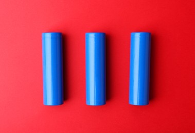 Photo of Three AA cell batteries on red background, top view