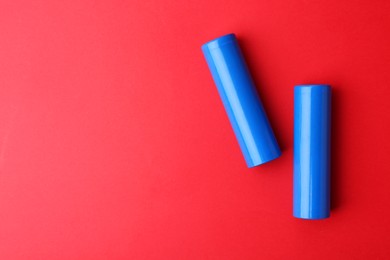 Photo of Two AA cell batteries on red background, top view. Space for text