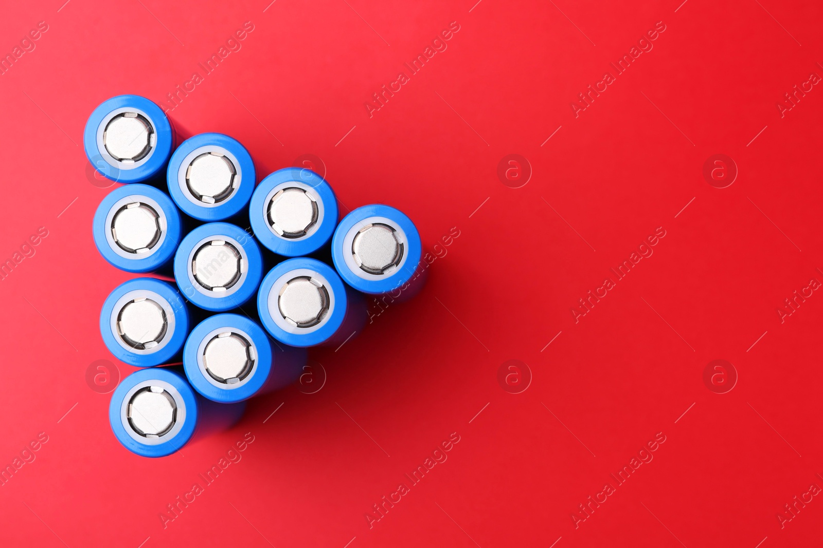 Photo of Many AA cell batteries on red background, top view. Space for text