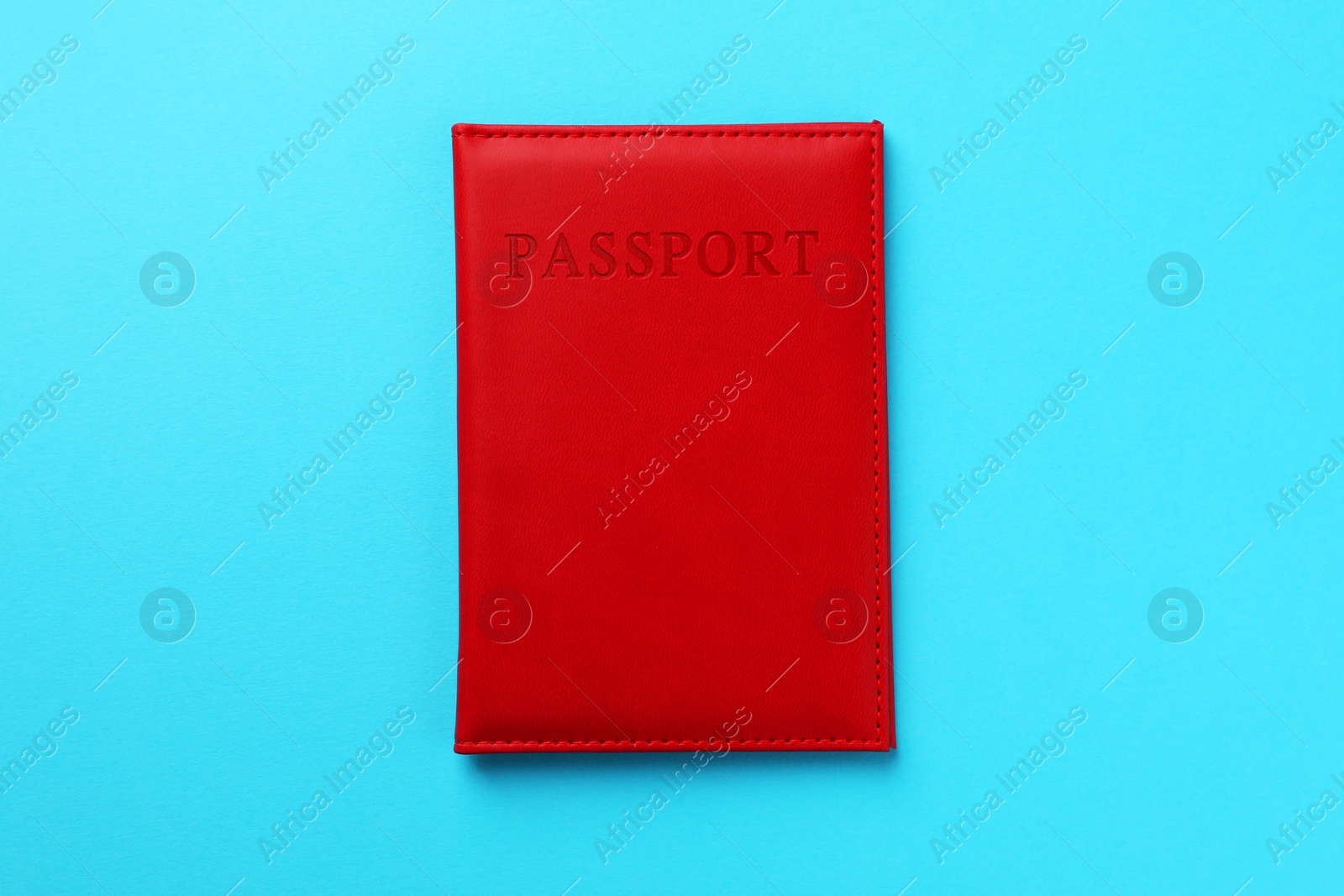 Photo of Passport in red cover on light blue background, top view