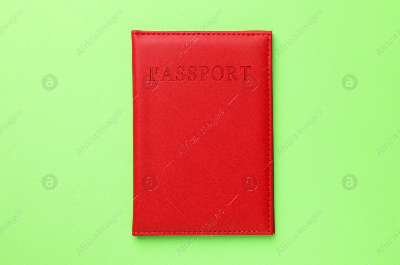 Photo of Passport in red cover on green background, top view