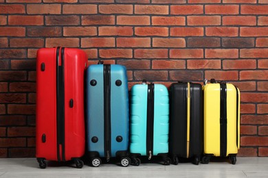 Photo of Many colorful suitcases on floor near brick wall