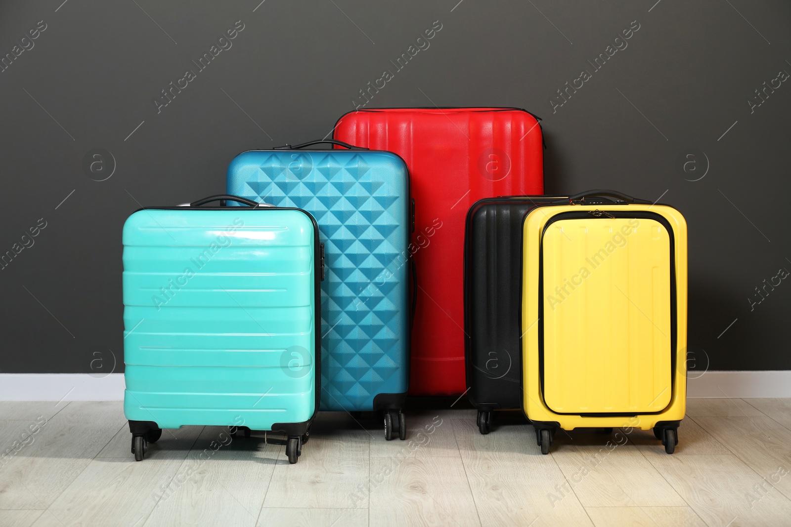 Photo of Colorful suitcases on floor near black wall