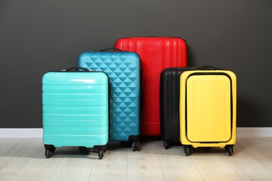 Photo of Colorful suitcases on floor near black wall