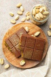 Photo of Pieces of Dubai chocolate bar with pistachios and knafeh on grey table, flat lay