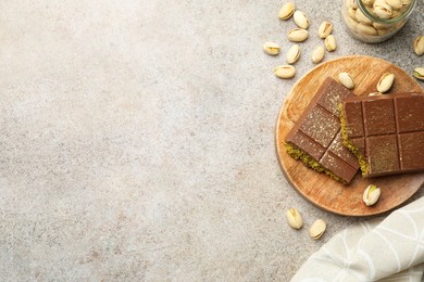 Photo of Pieces of Dubai chocolate bar with pistachios and knafeh on grey table, flat lay. Space for text