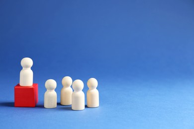 Photo of Competition concept. Human figure on wooden cube and other ones behind against blue background, space for text