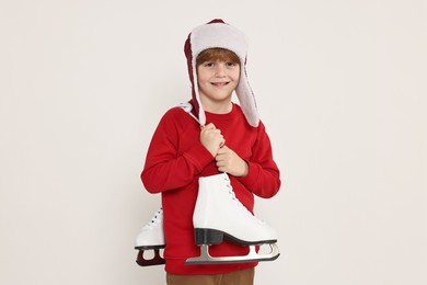 Photo of Little boy in hat with ice skates on light grey background