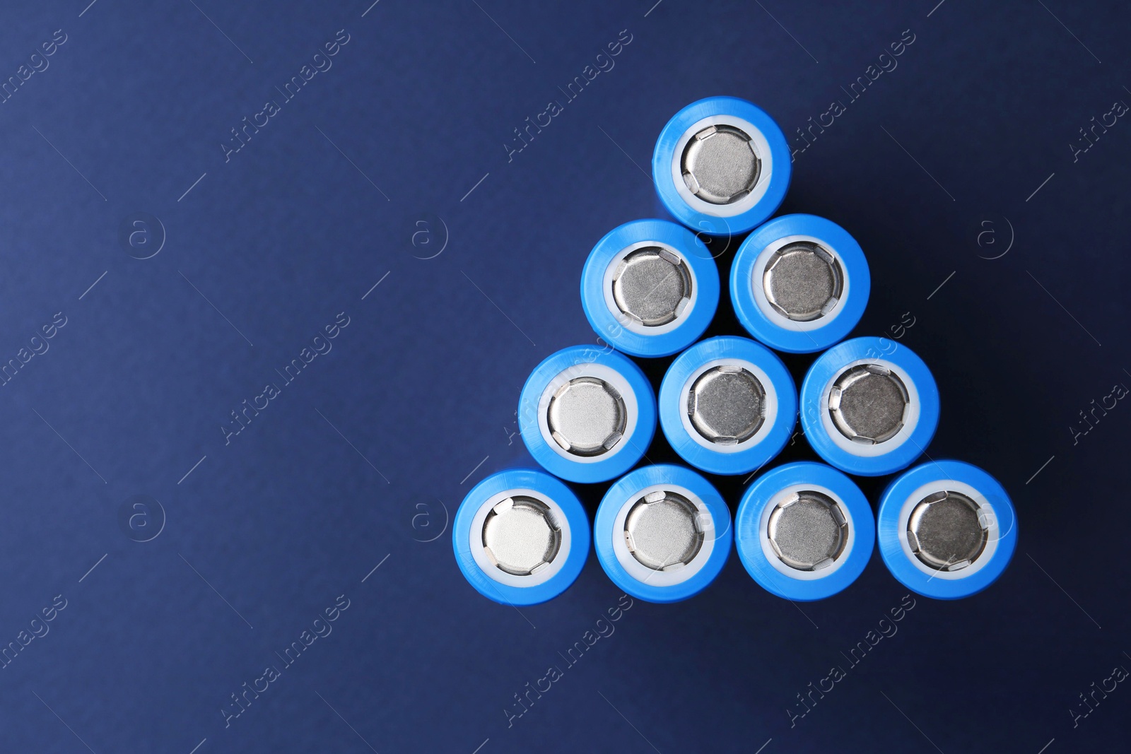 Photo of Many AA cell batteries on blue background, top view. Space for text