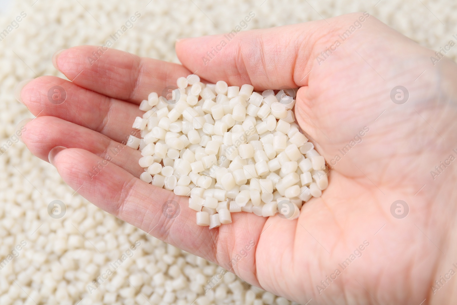 Photo of Woman with plastic granules on blurred background, closeup