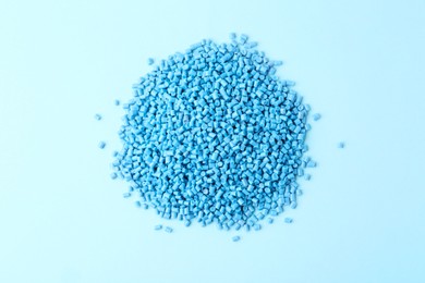 Photo of Pile of plastic granules on light blue background, top view