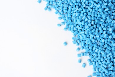 Photo of Pile of light blue plastic granules on white background, top view. Space for text