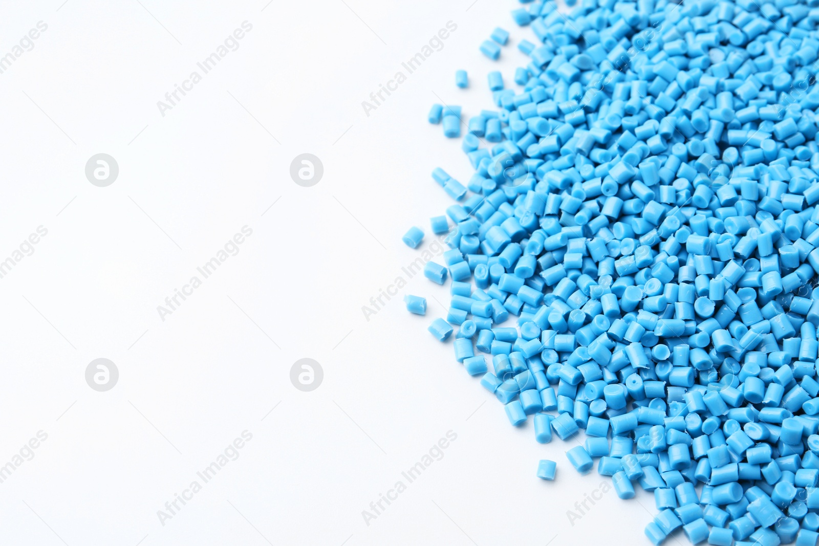 Photo of Pile of light blue plastic granules on white background, closeup. Space for text