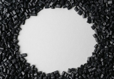 Photo of Frame of black plastic granules on grey background, top view. Space for text