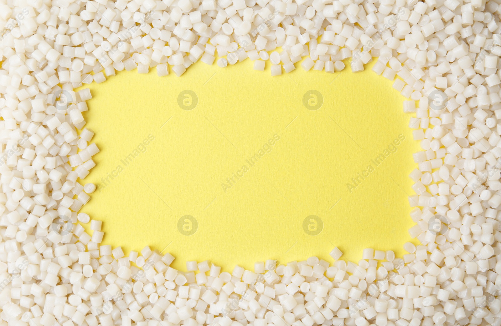 Photo of Frame of plastic granules on yellow background, top view. Space for text