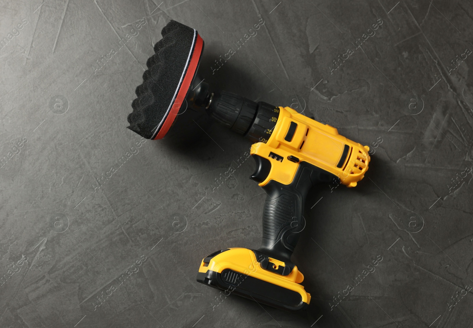 Photo of Electric screwdriver with polish pad on grey table, top view