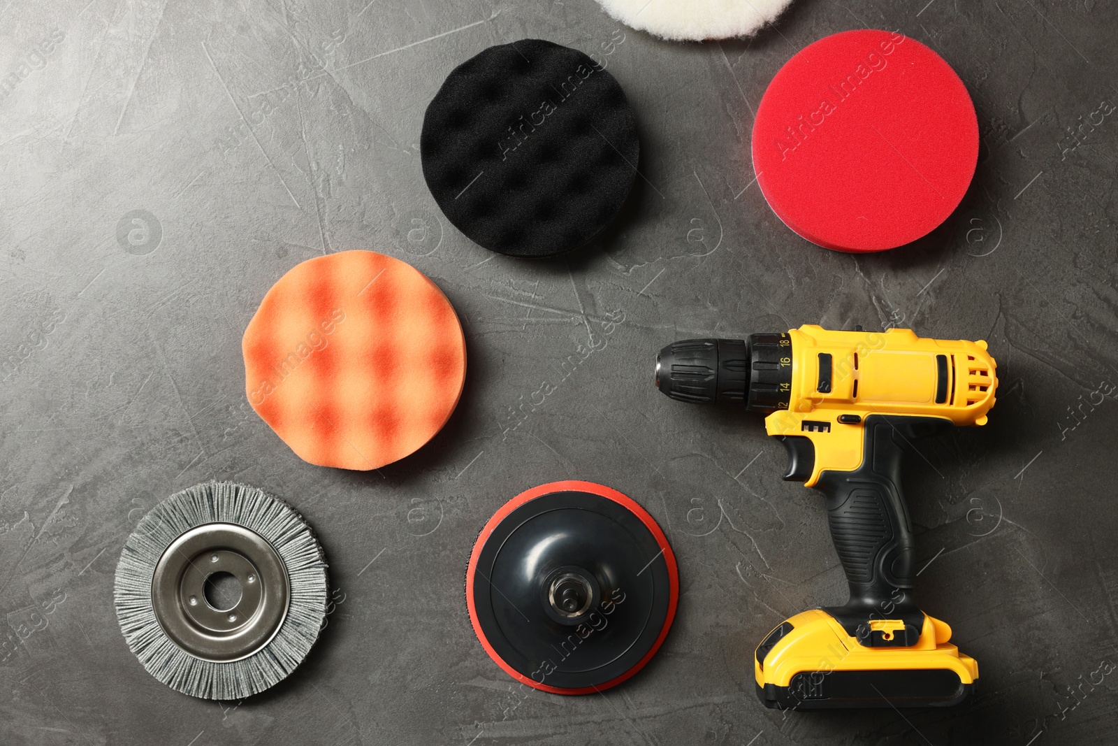 Photo of Electric screwdriver and polish pads on grey table, flat lay