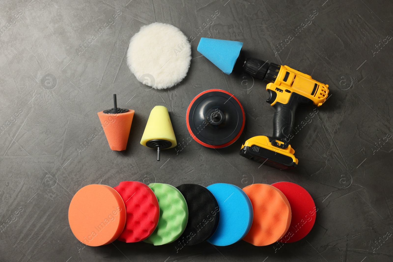 Photo of Electric screwdriver and polish pads on grey table, flat lay