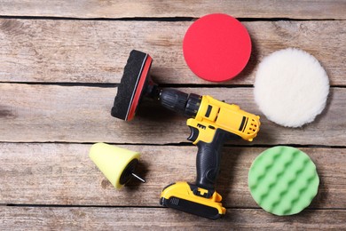 Photo of Electric screwdriver and polish pads on wooden table, flat lay