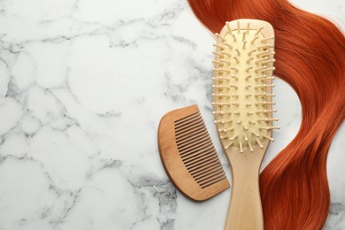 Photo of Wooden brush, comb and lock of hair on white marble table, flat lay. Space for text