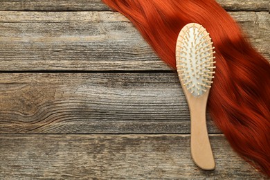 Photo of Brush and lock of hair on wooden table, top view. Space for text