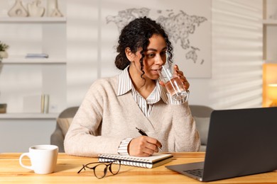 Photo of Beautiful woman working on laptop at desk in home office