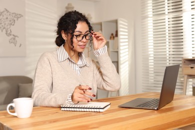 Photo of Beautiful woman working on laptop at desk in home office