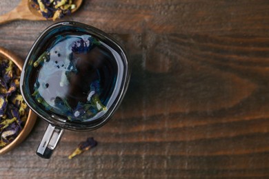 Photo of Delicious butterfly pea flower tea on wooden table, flat lay. Space for text