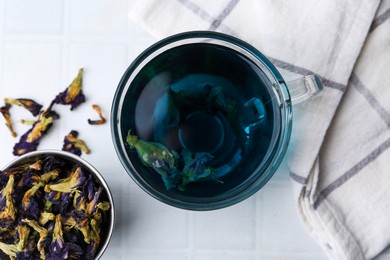 Delicious butterfly pea flower tea on white tiled table, flat lay