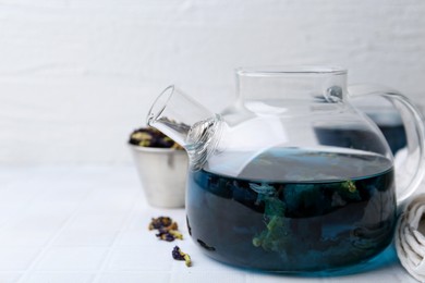 Photo of Delicious butterfly pea flower tea on white tiled table. Space for text