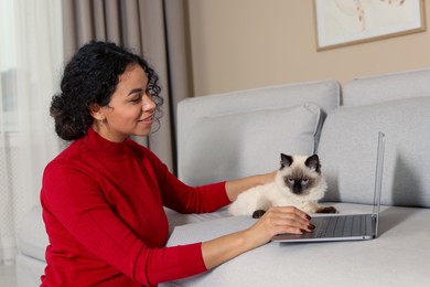 Photo of Beautiful woman with her cute cat working on laptop at home