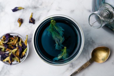 Photo of Delicious butterfly pea flower tea on white marble table, flat lay