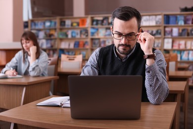 Photo of Man working with laptop at desk in public library