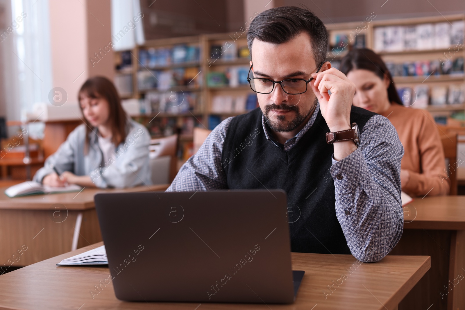 Photo of Man working with laptop at desk in public library