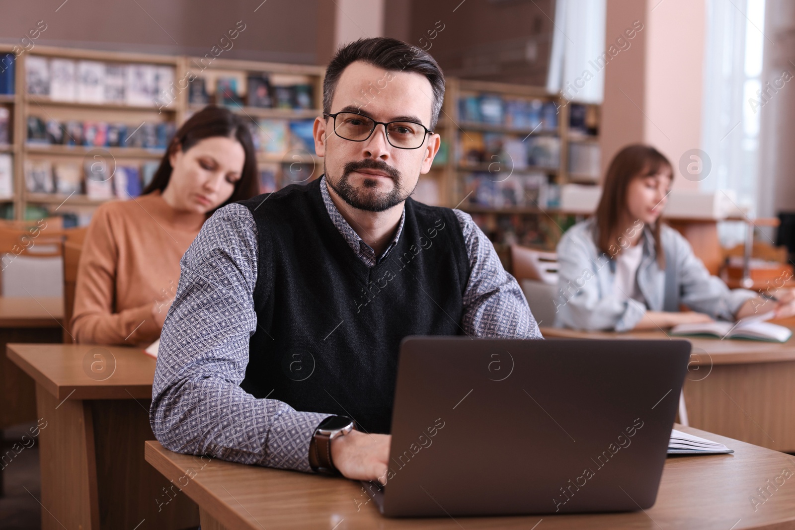 Photo of Portrait of man with laptop at desk in public library