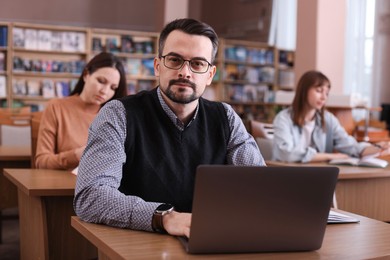 Photo of Portrait of man with laptop at desk in public library