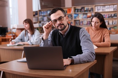 Photo of Portrait of man with laptop at desk in public library