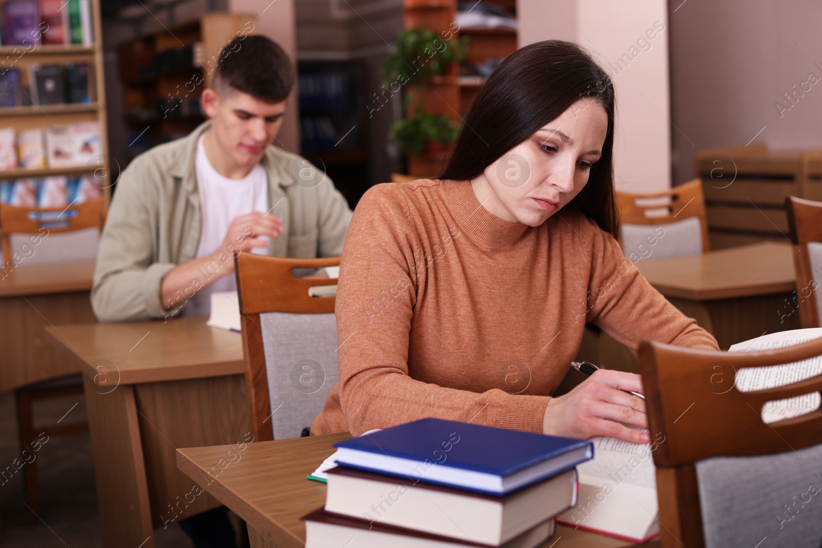 Photo of Beautiful woman with books at desk in public library