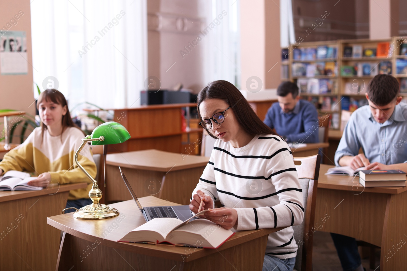 Photo of Group of people working at desks in public library