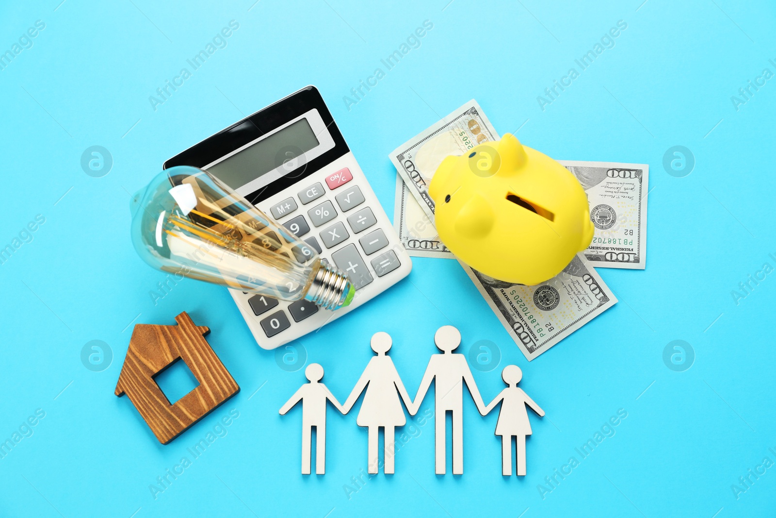 Photo of Flat lay composition with piggy bank and lightbulb on light blue background. Energy saving concept