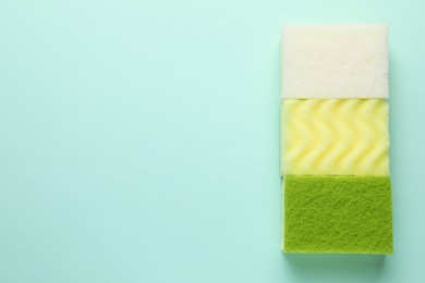 Photo of Colorful sponges on light blue background, top view. Space for text