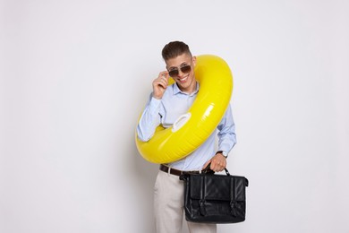 Photo of Businessman with inflatable ring and briefcase on white background