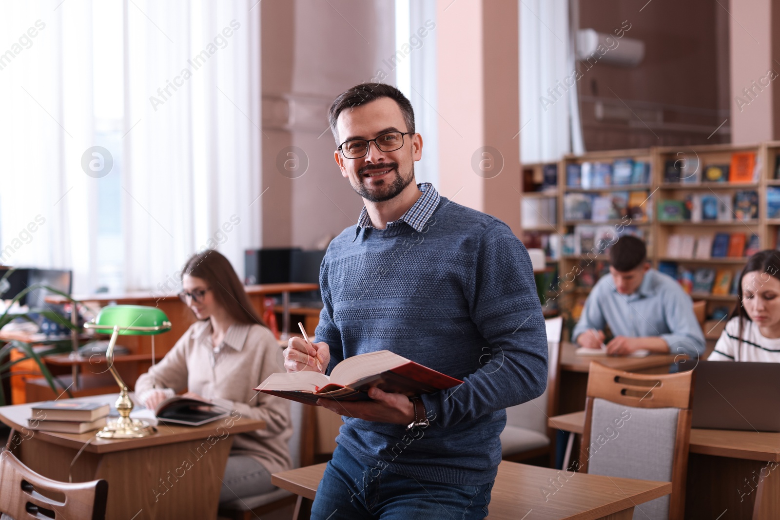 Photo of Portrait of smiling man with book in library