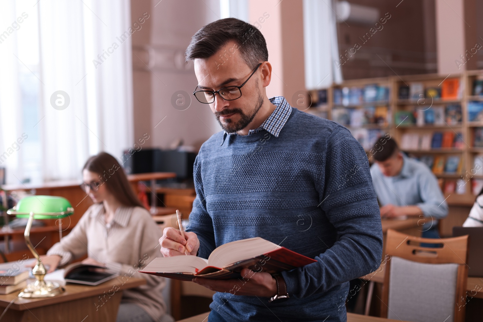 Photo of Handsome man with book in public library