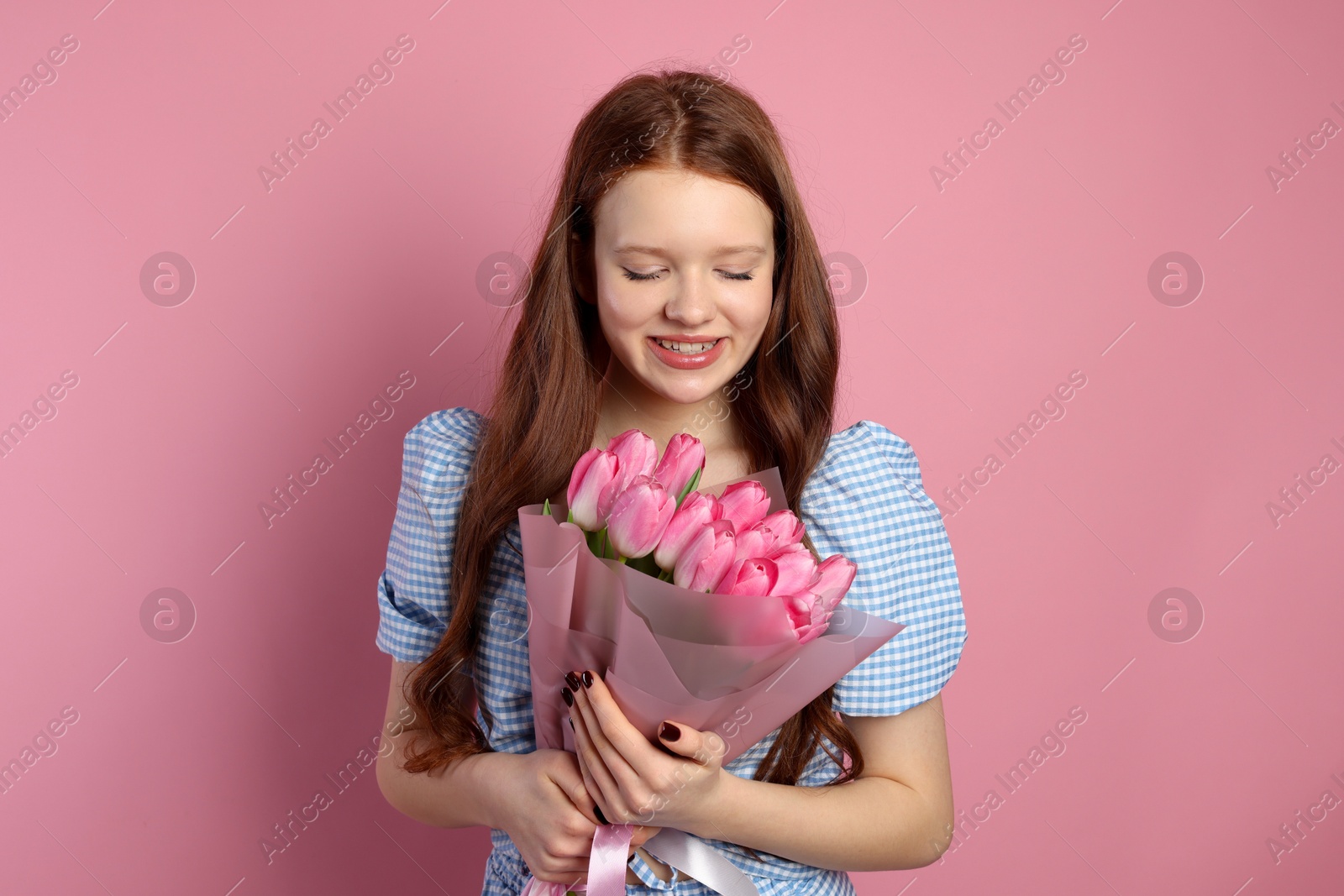 Photo of Beautiful teenage girl with bouquet of tulips on pink background