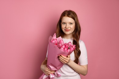 Photo of Beautiful teenage girl with bouquet of tulips on pink background