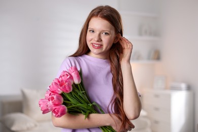 Photo of Beautiful teenage girl with bouquet of tulips indoors