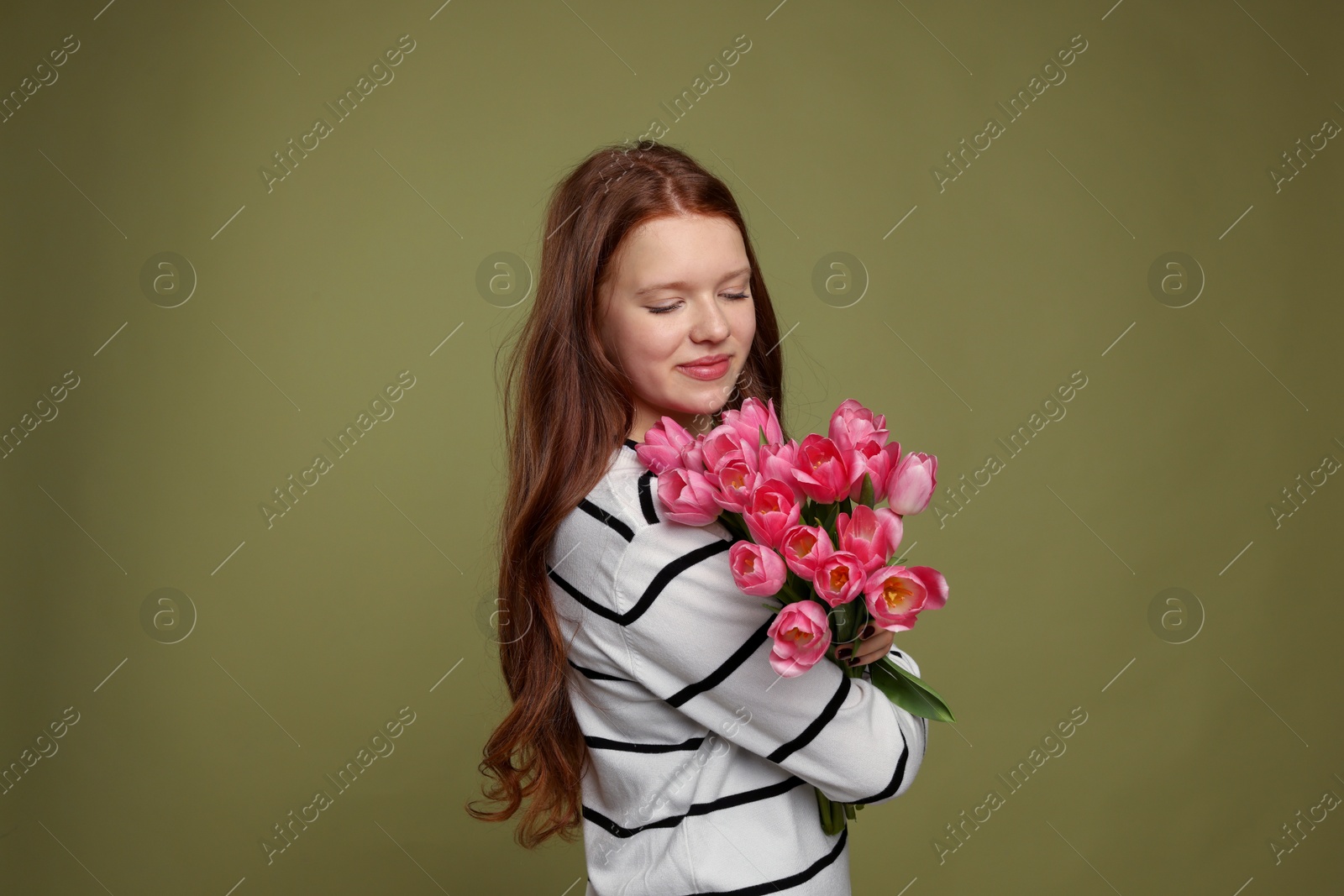 Photo of Beautiful teenage girl with bouquet of tulips on olive background